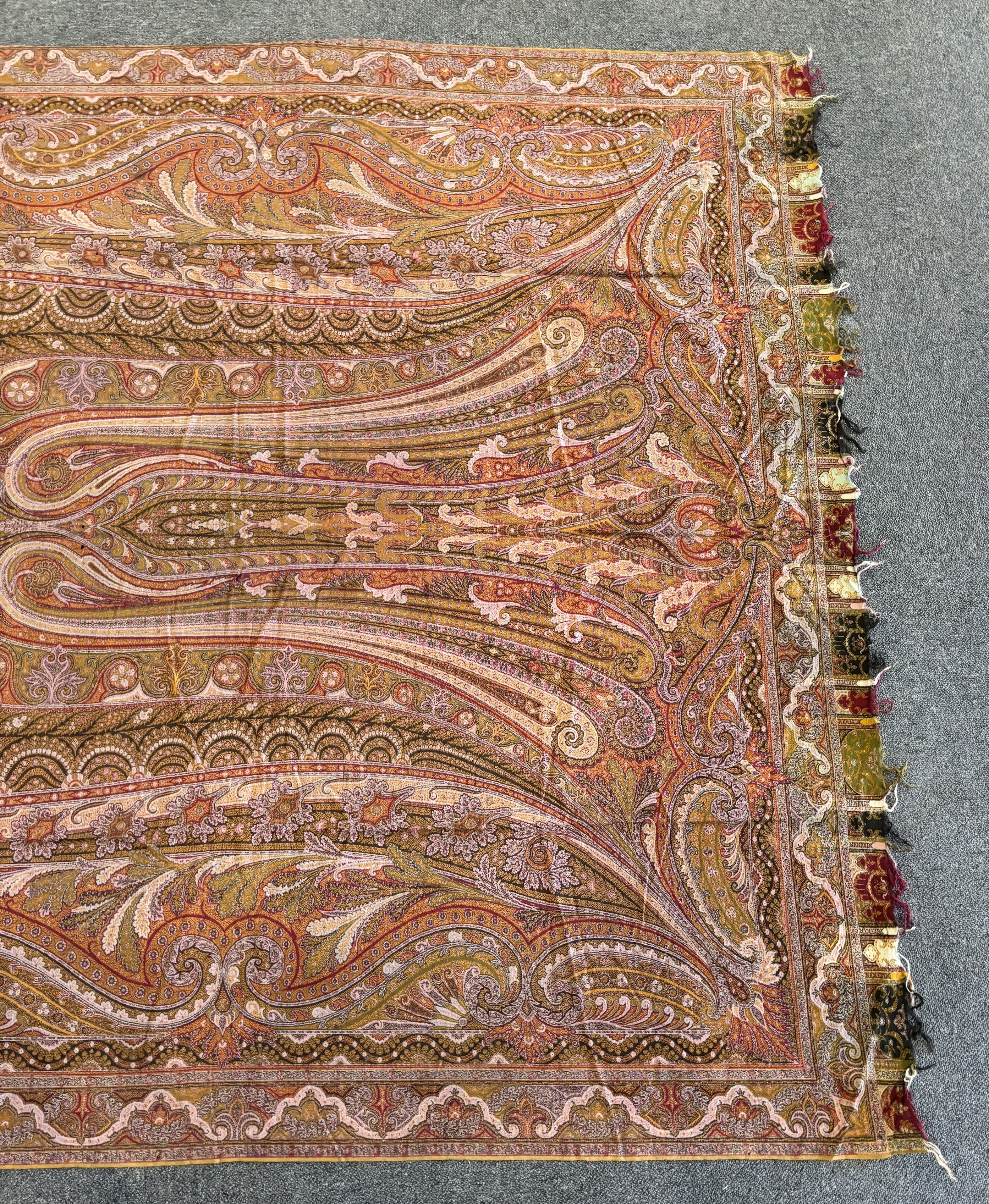 A 19th century woven Scottish Paisley wool shawl, bordered on four sides and fringed on two, woven with two ornate teardrop designs and a central cartouche, 334cm long x 160cm wide